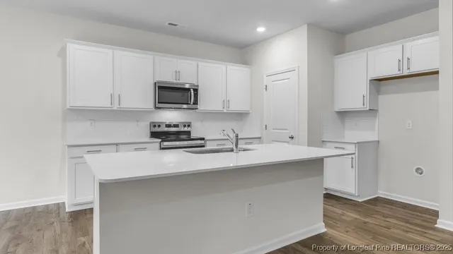 a kitchen with stainless steel appliances a sink a stove a refrigerator and white cabinets