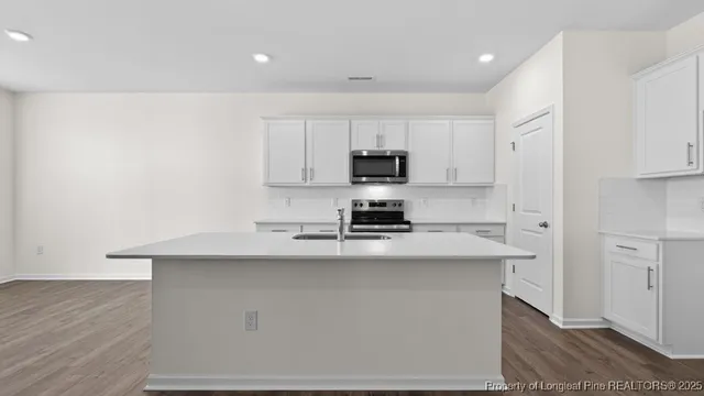 a kitchen with stainless steel appliances a sink a stove a refrigerator cabinets and a counter space
