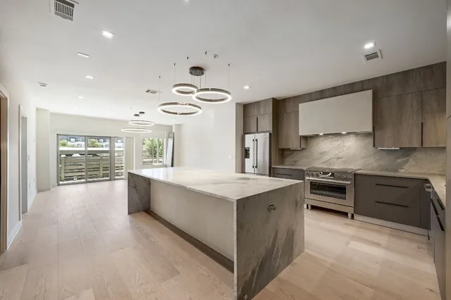 a large kitchen with stainless steel appliances granite countertop a lot of counter space and wooden floors