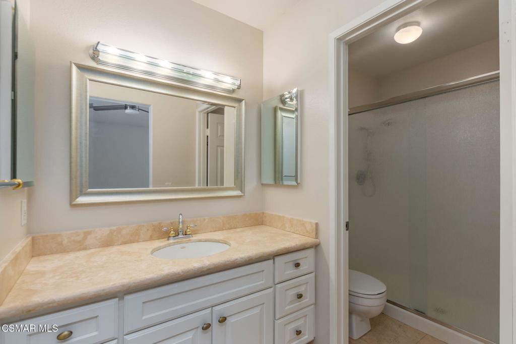 1047 Windmill Lane Oak Park, CA 91377 - Photo 9 of 13 a bathroom with a granite countertop sink a toilet and a mirror
