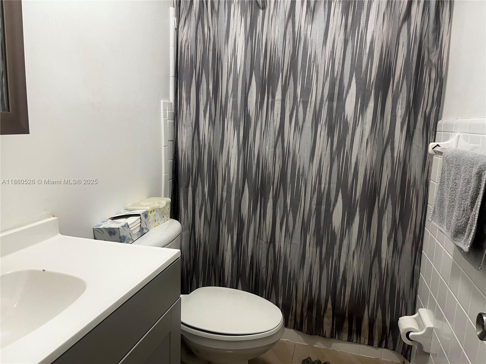 1821 Northeast 56th Street, Unit 4 Fort Lauderdale, FL 33308 - Photo 8 of 9 a bathroom with a sink a toilet and shower curtain