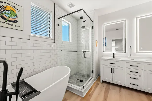 a bathroom with a tub a double vanity sink a mirror a shower and a bathtub