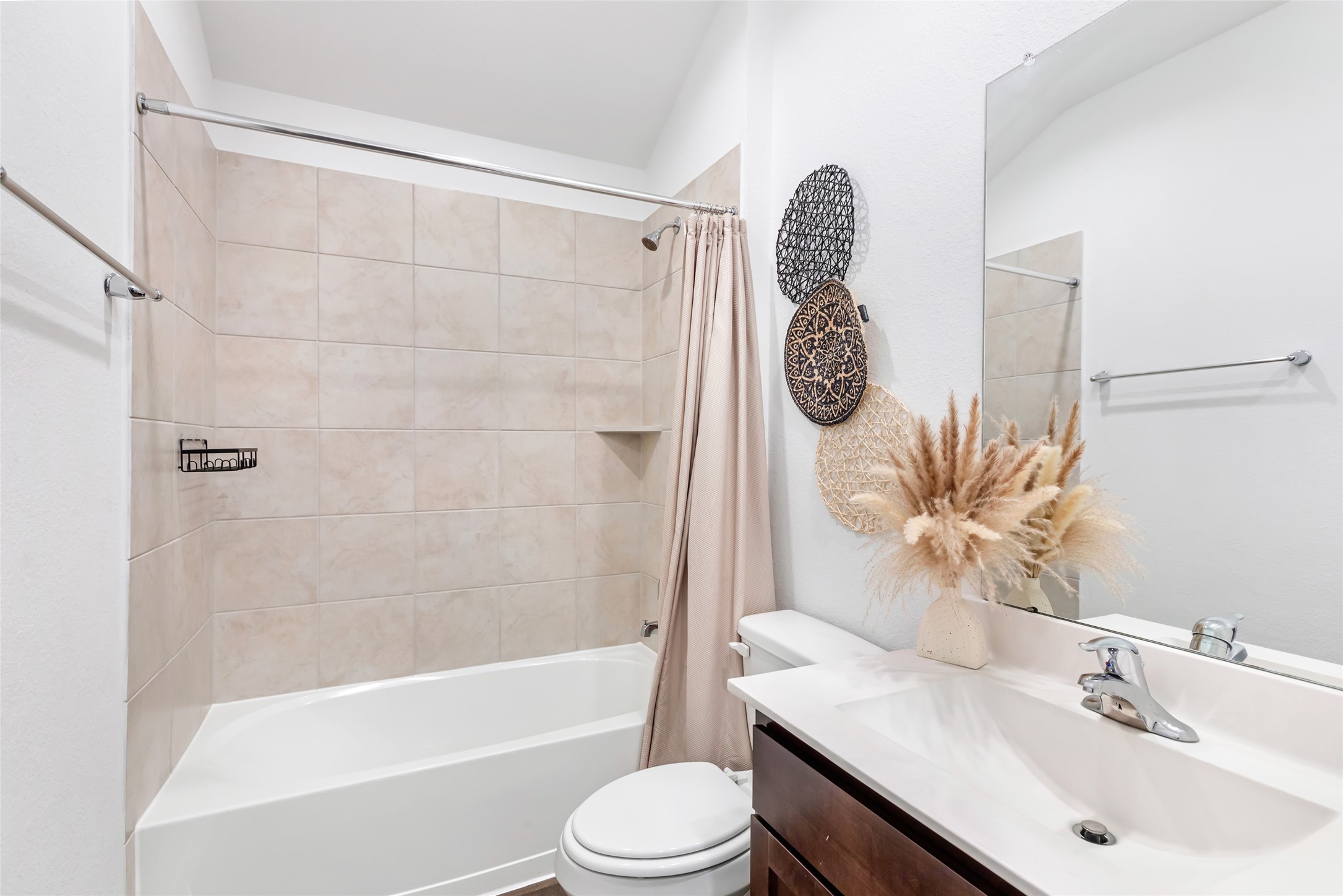 811 Republic Road New Caney, TX 77357 - Photo 18 of 37 This bathroom features a clean, modern design with neutral tile walls in the bathtub area, a sleek white sink, and dark wood cabinetry. Decorative elements and a vase with dried plants add a touch of elegance.