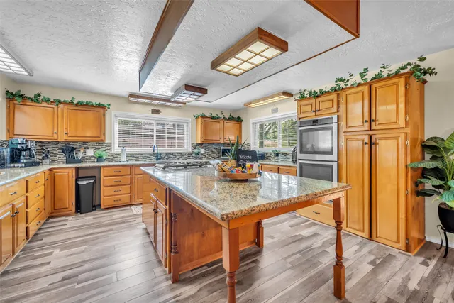 a kitchen with stainless steel appliances granite countertop a refrigerator a stove and a wooden floors