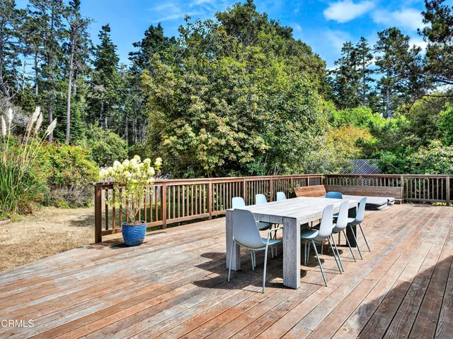 a balcony with wooden floor table and chairs