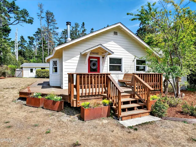 a view of a house with wooden deck and furniture