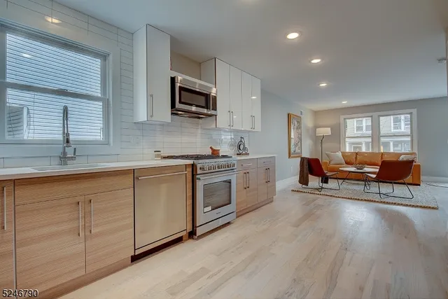 a kitchen with stainless steel appliances granite countertop a stove a sink dishwasher and a microwave oven with white cabinets