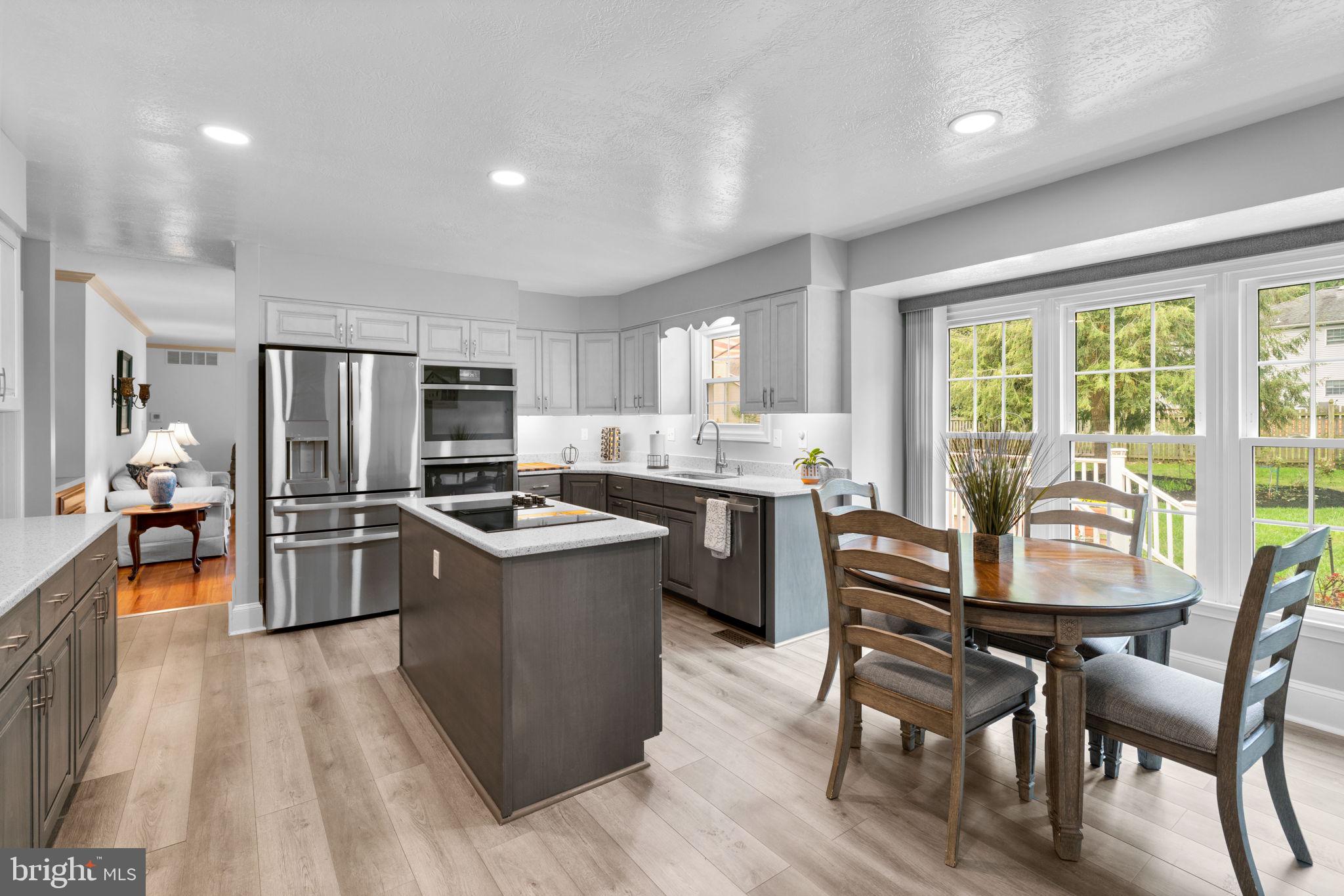 7884 Walnut Grove Road Severn, MD 21144 - Photo 5 of 42 a kitchen with stainless steel appliances granite countertop a stove a sink dishwasher a refrigerator and a dining table with wooden floor