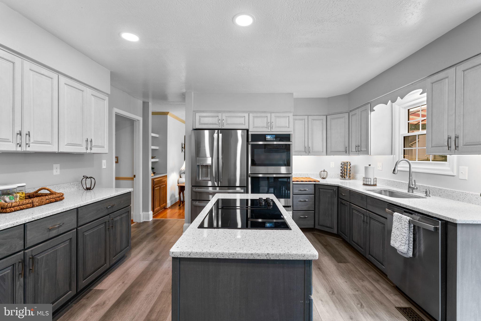 7884 Walnut Grove Road Severn, MD 21144 - Photo 6 of 42 a kitchen with stainless steel appliances kitchen island granite countertop a sink a stove top oven a refrigerator cabinets and a center island