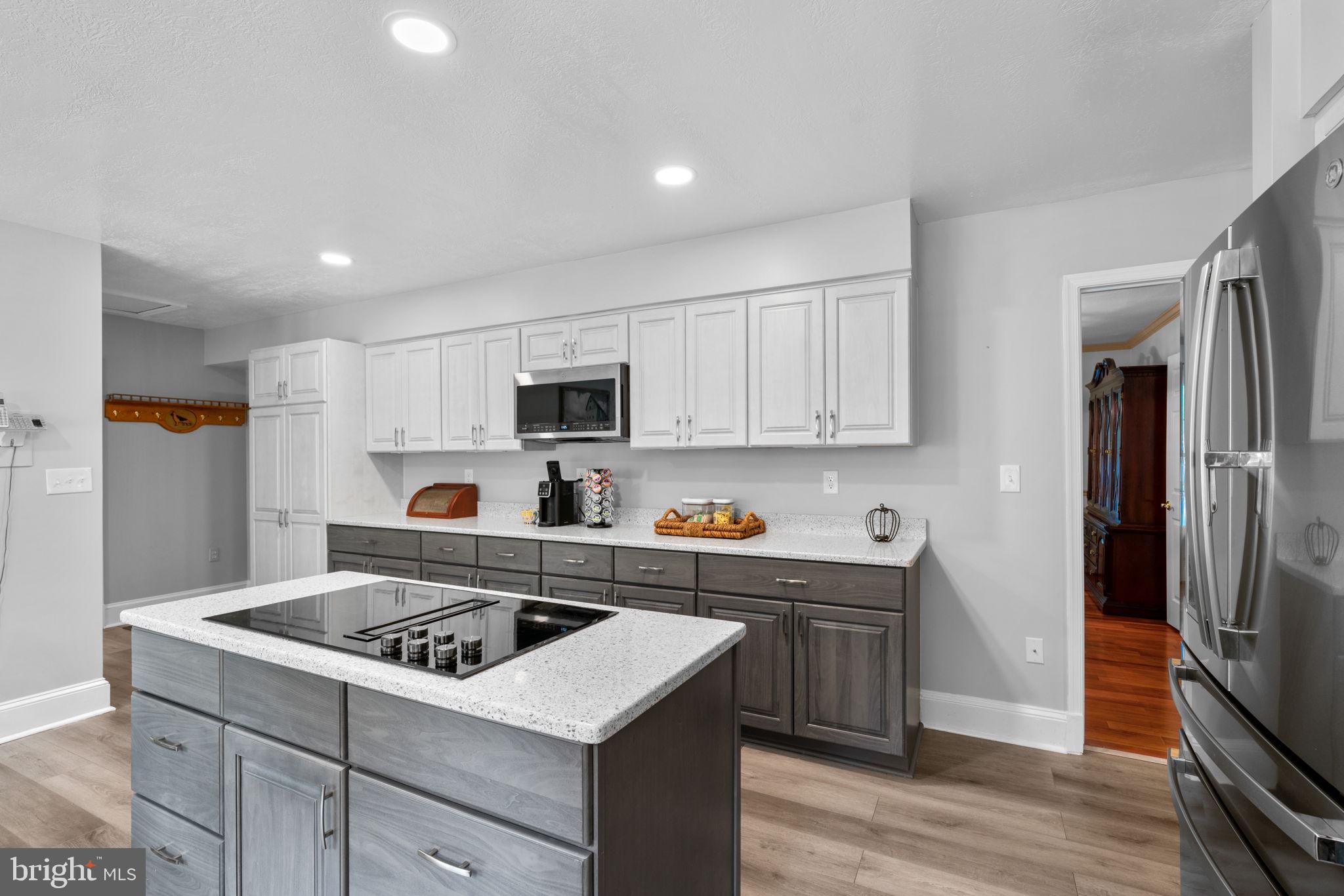 7884 Walnut Grove Road Severn, MD 21144 - Photo 7 of 42 a kitchen with stainless steel appliances a stove a sink dishwasher a refrigerator and white cabinets with wooden floor