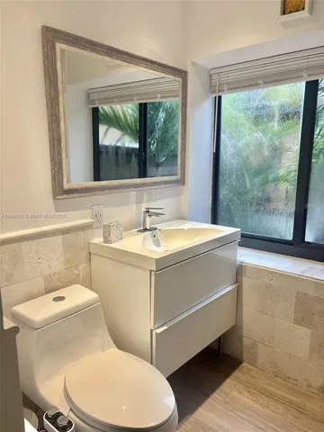 a bathroom with a sink mirror toilet and next to a window