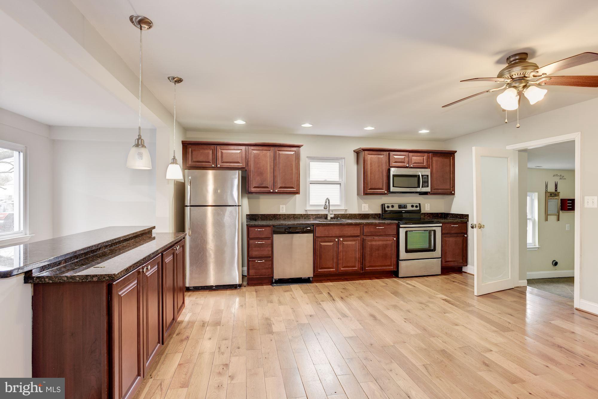 3220 Rolling Rd. Baltimore, MD 21244 - Photo 10 of 28 a kitchen with stainless steel appliances kitchen island granite countertop wooden floors and a refrigerator