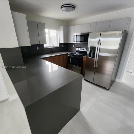 a kitchen with granite countertop a refrigerator a sink a stove a microwave a counter top and oven