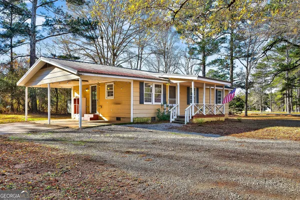 a view of a house with a yard and large trees