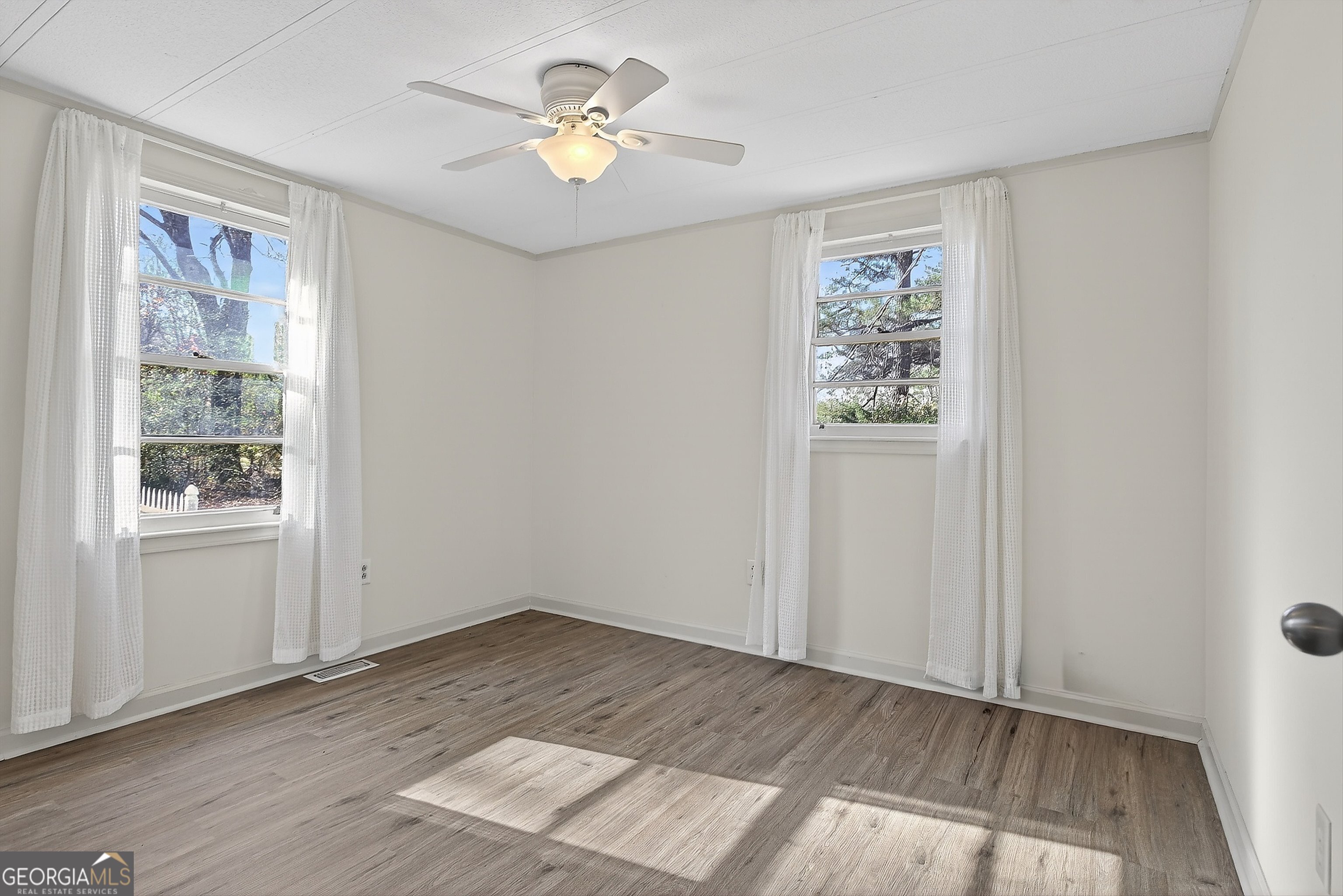 1470 Melville Brown Road Williamson, GA 30292 - Photo 9 of 36 an empty room with wooden floor chandelier fan and windows