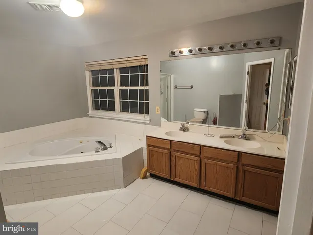 a spacious bathroom with a tub sink and mirror