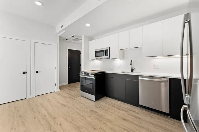 a kitchen with a refrigerator and white cabinets