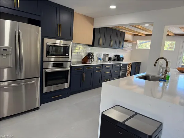 a kitchen with granite countertop a refrigerator stove and sink