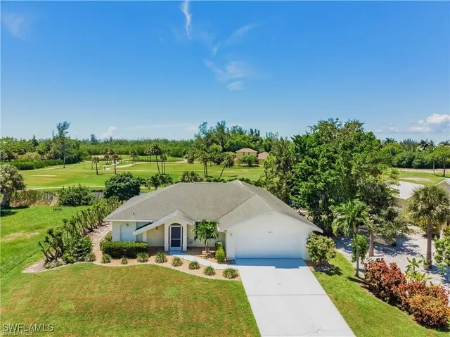 a view of a house with a big yard plants and large trees