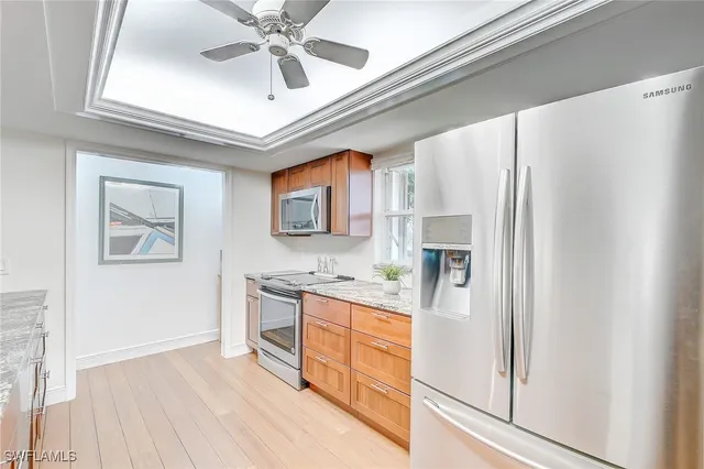 a kitchen with stainless steel appliances granite countertop a refrigerator a stove and white cabinets with wooden floor