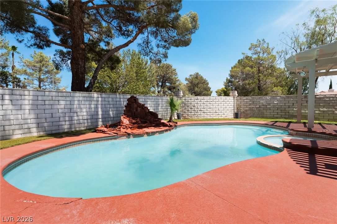 9028 Cypress Point Road Las Vegas, NV 89117 - Photo 33 of 39 An inviting backyard oasis offers a pristine pool and a cozy hot tub under a bright blue sky.