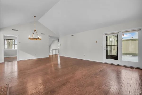 a view of an empty room with wooden floor fireplace and a window