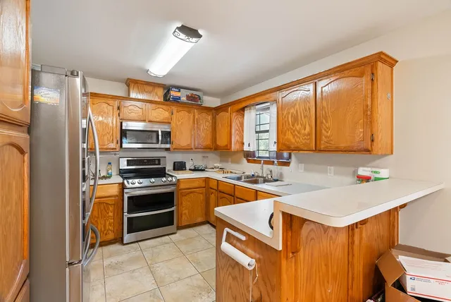 a kitchen with stainless steel appliances granite countertop a sink stove refrigerator and microwave