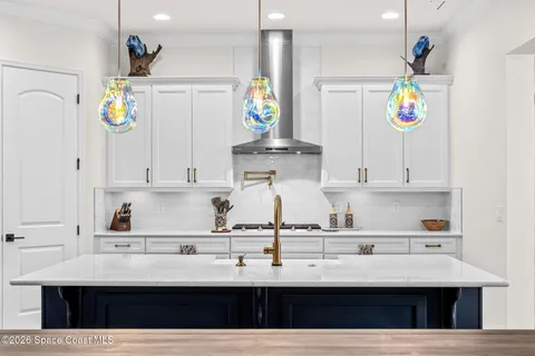 a kitchen with kitchen island granite countertop a sink a stove and white cabinets