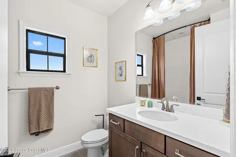 a bathroom with a toilet a sink a mirror a vanity and window