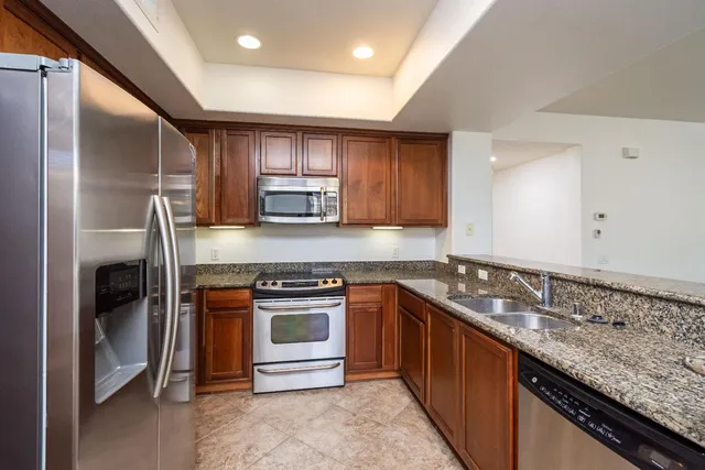 a kitchen with kitchen island granite countertop a sink stainless steel appliances and cabinets
