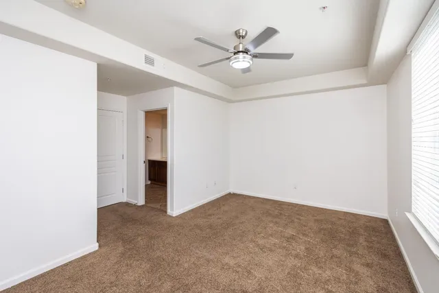 an empty room with windows and fan