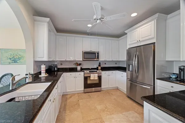 a kitchen with granite countertop a refrigerator a sink a stove a microwave and island
