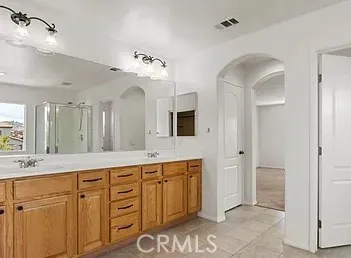 a spacious bathroom with a double vanity sink a mirror and a shower