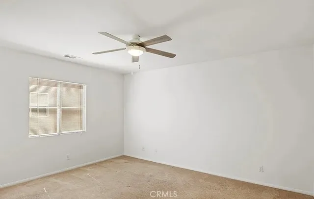 an empty room with windows and fan