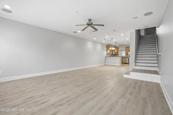 an empty room with wooden floor ceiling fan and windows