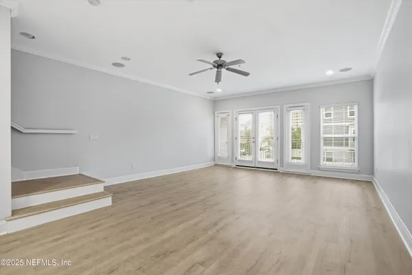 a view of an empty room with a window and wooden floor