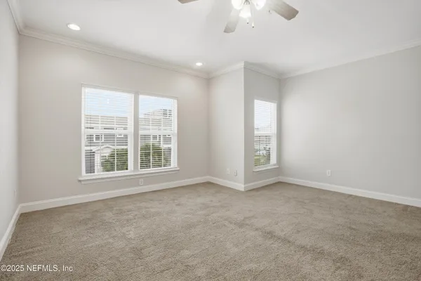 an empty room with windows and chandelier fan