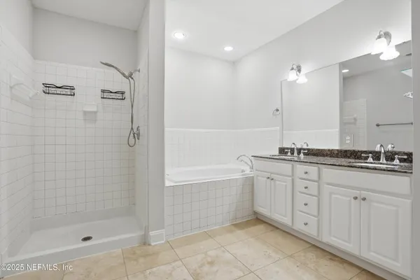 a bathroom with a granite countertop sink a mirror a bathtub and shower