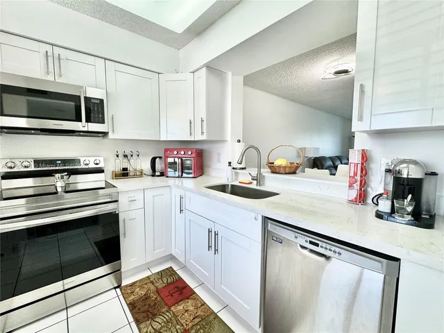 a kitchen with stainless steel appliances granite countertop a sink dishwasher stove and microwave with wooden cabinets