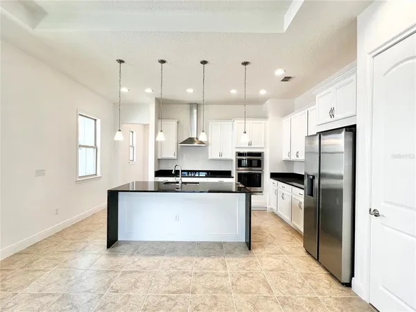 a kitchen with stainless steel appliances kitchen island granite countertop a refrigerator and a sink