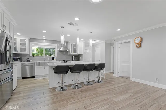 a kitchen with kitchen island stainless steel appliances a dining table chairs sink and cabinets
