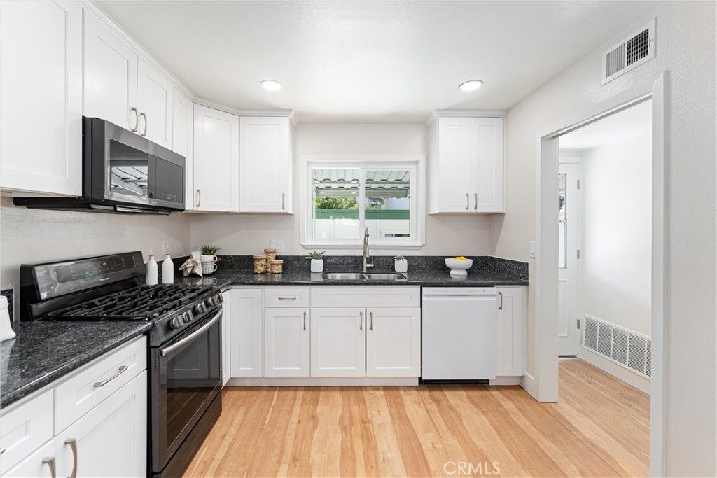 8236 Henderson Green Buena Park, CA 90621 - Photo 12 of 35 a kitchen with stainless steel appliances a sink a stove a microwave and cabinets