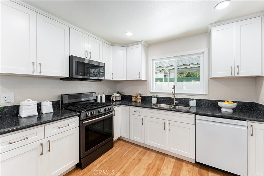 8236 Henderson Green Buena Park, CA 90621 - Photo 13 of 35 a kitchen with granite countertop white cabinets sink and stainless steel appliances