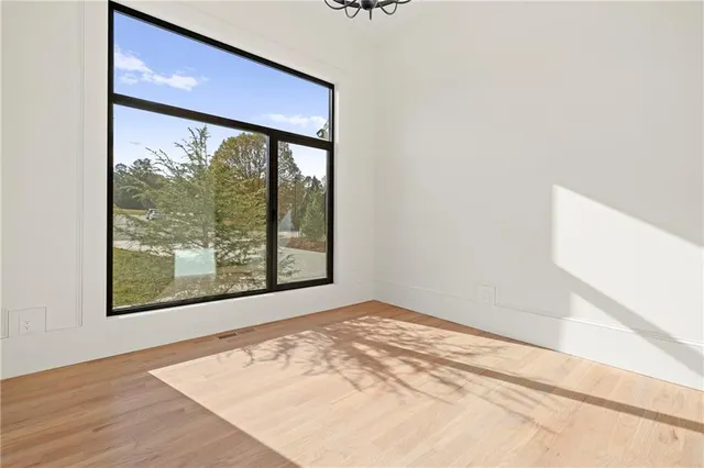 an empty room with wooden floor cabinet and windows