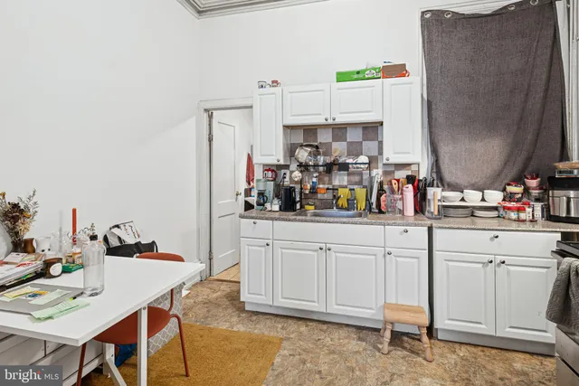 a kitchen with white cabinets and chairs