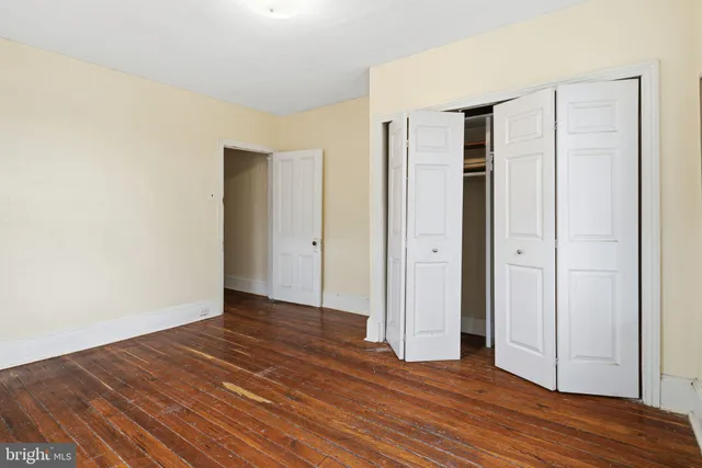 a view of an empty room with wooden floor and closet