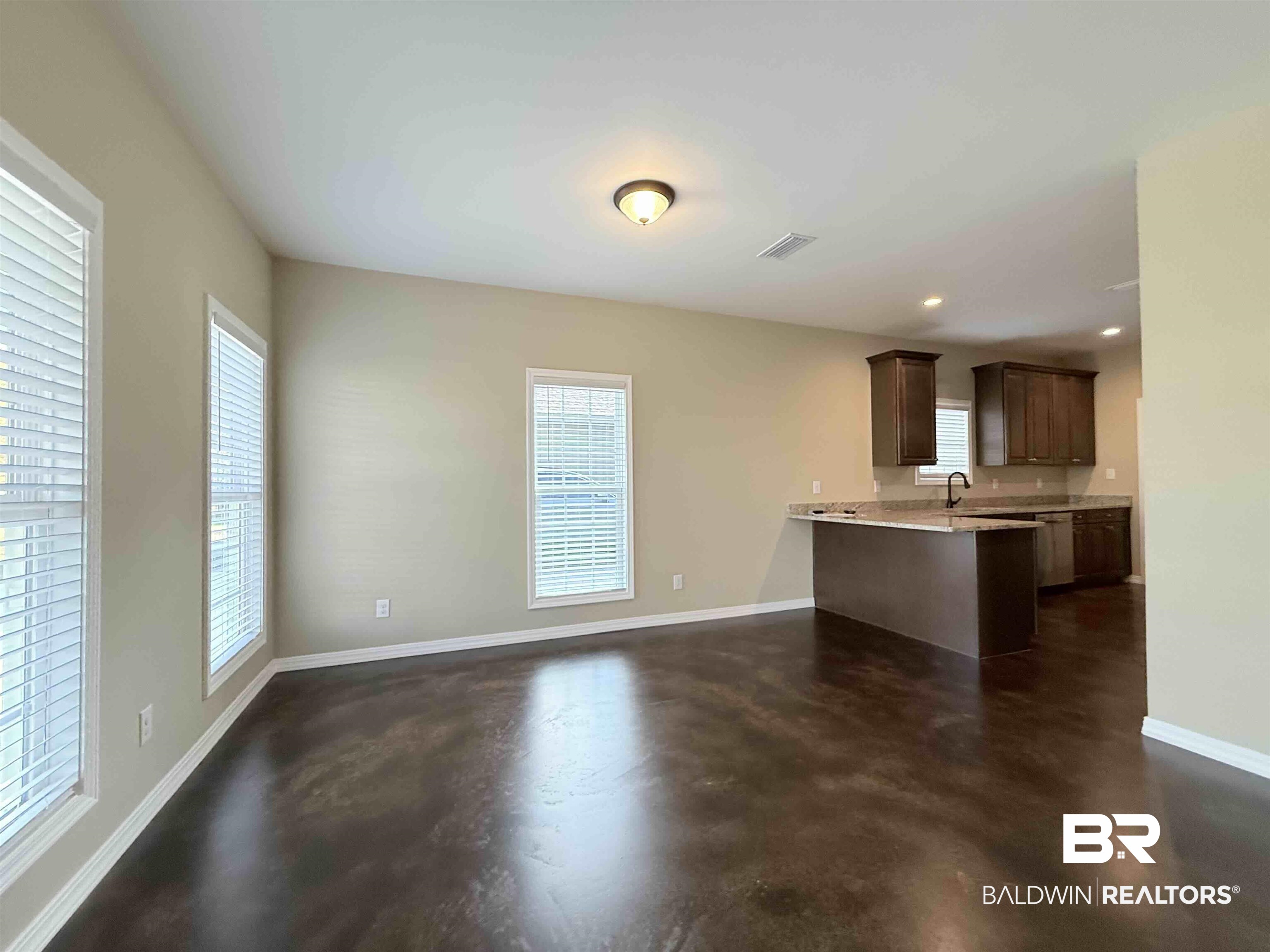 33071 -B Stables Drive, Unit B Daphne, AL 36527 - Photo 3 of 13 Kitchen featuring dark brown cabinets, a peninsula, concrete flooring, light stone counters, and recessed lighting