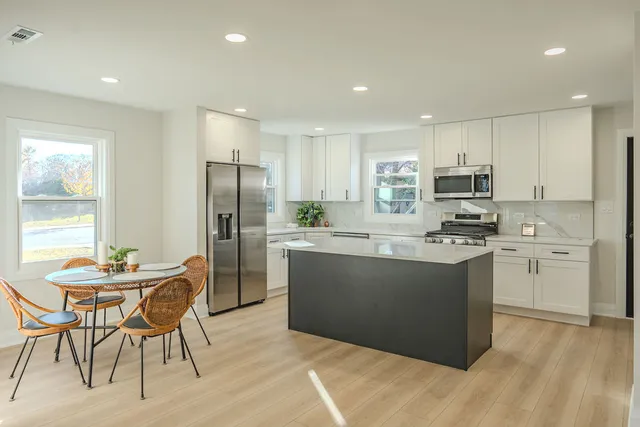 a kitchen with kitchen island white cabinets and stainless steel appliances