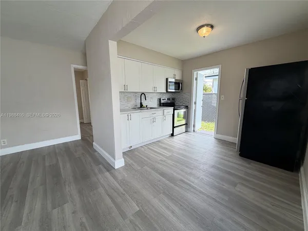 a view of a kitchen with wooden floor and a refrigerator