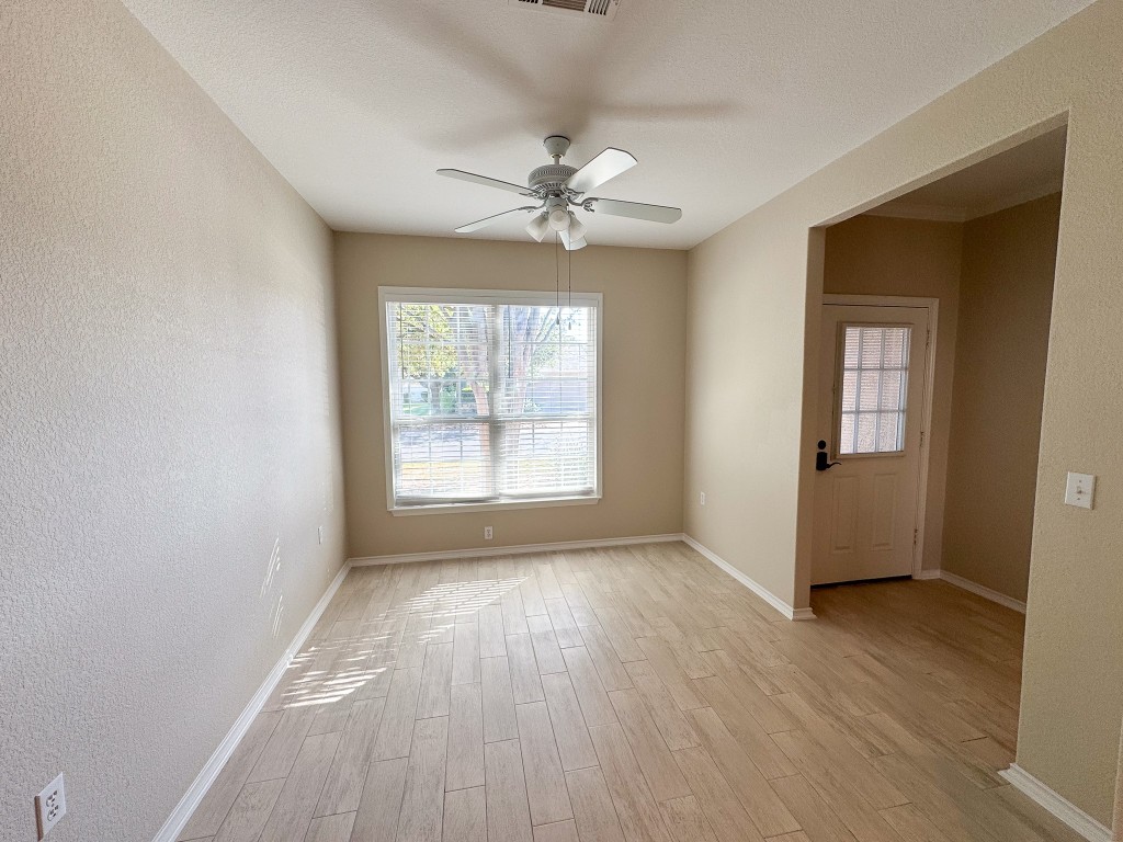 100 Sunbird Court Georgetown, TX 78633 - Photo 7 of 40 Empty room featuring a textured wall, light wood-style floors, healthy amount of natural light, and a ceiling fan